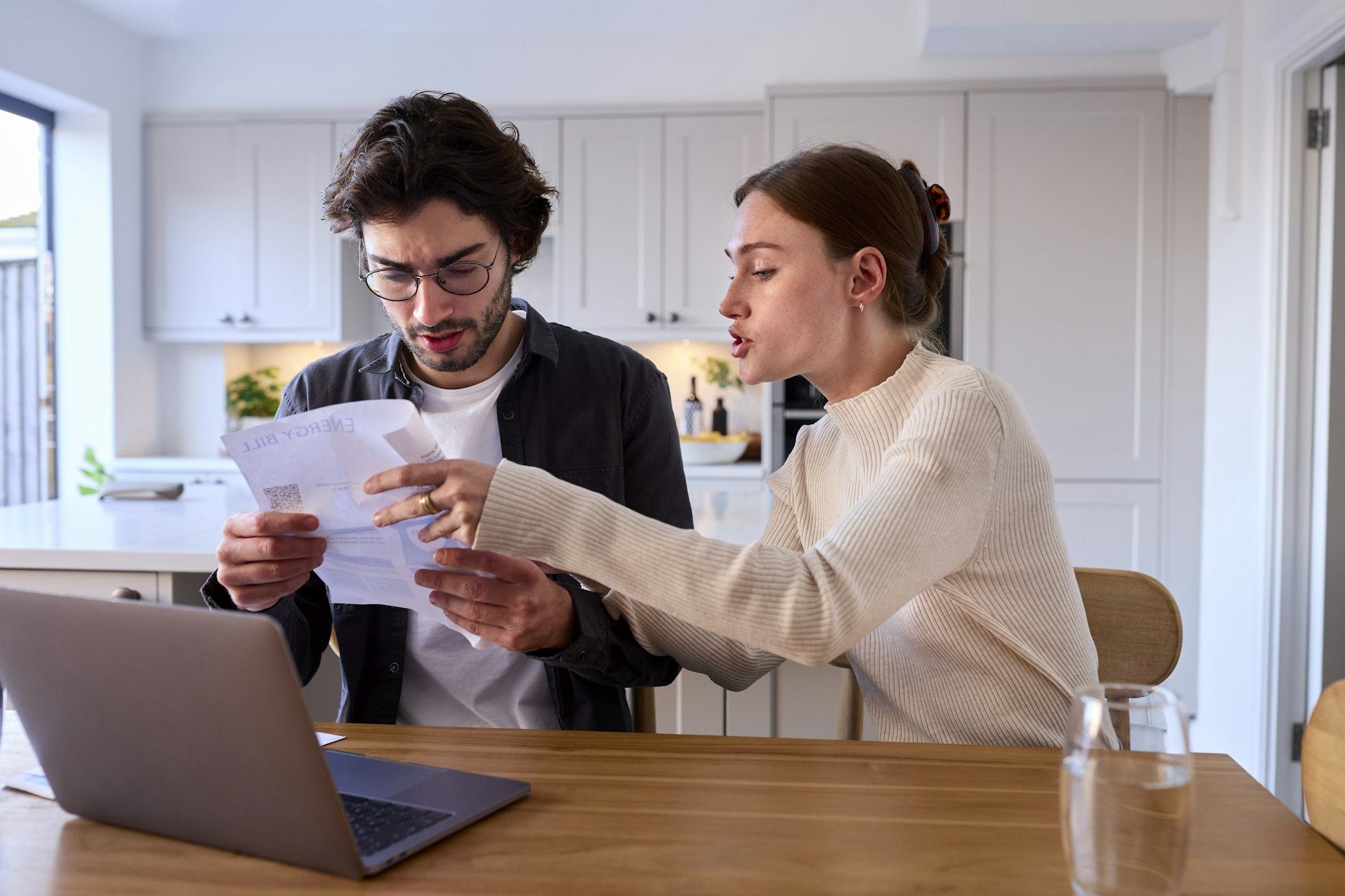 Worried Couple At Home Looking At Laptop Holding Energy Bill